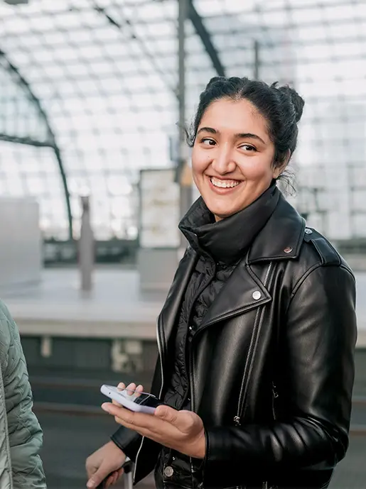 Hochverfügbarkeit: Glückliche Bahnkundin mit Smartphone in der Hand